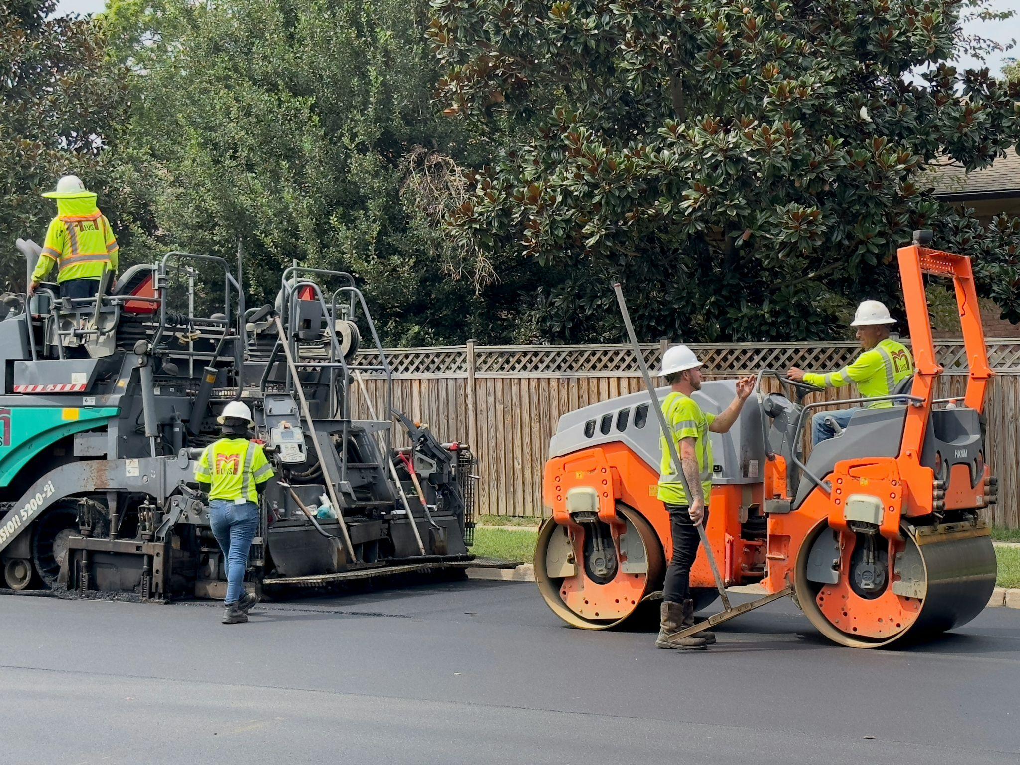 A road roller compacts fresh asphalt for California asphalt resurfacing.