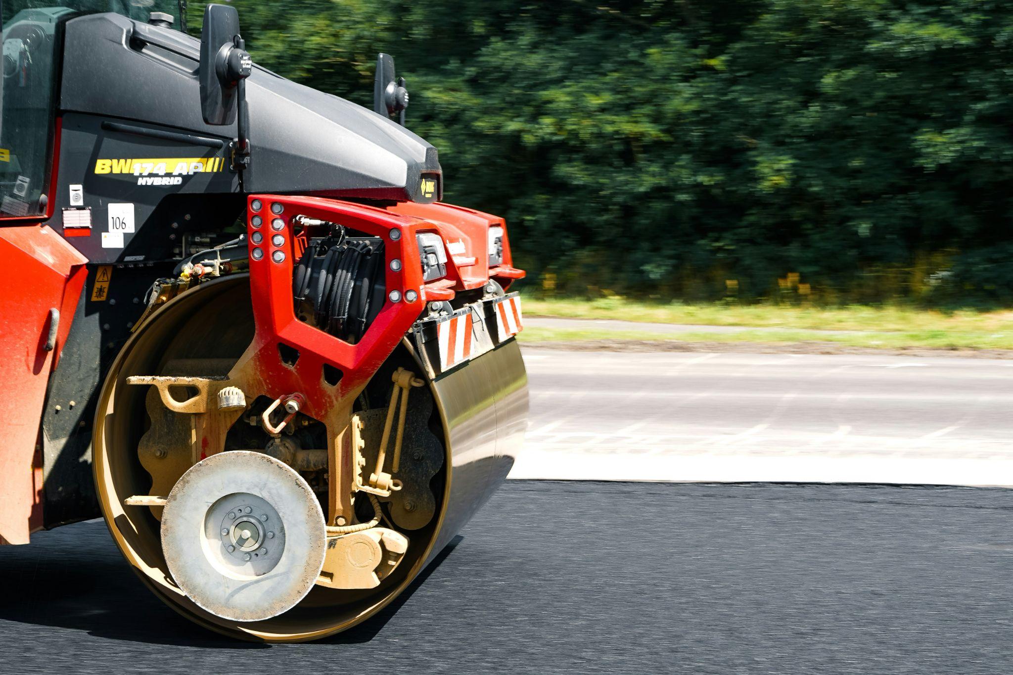 A road roller compacts fresh asphalt to create a smooth, durable surface as part of asphalt sealcoating services in Clovis.