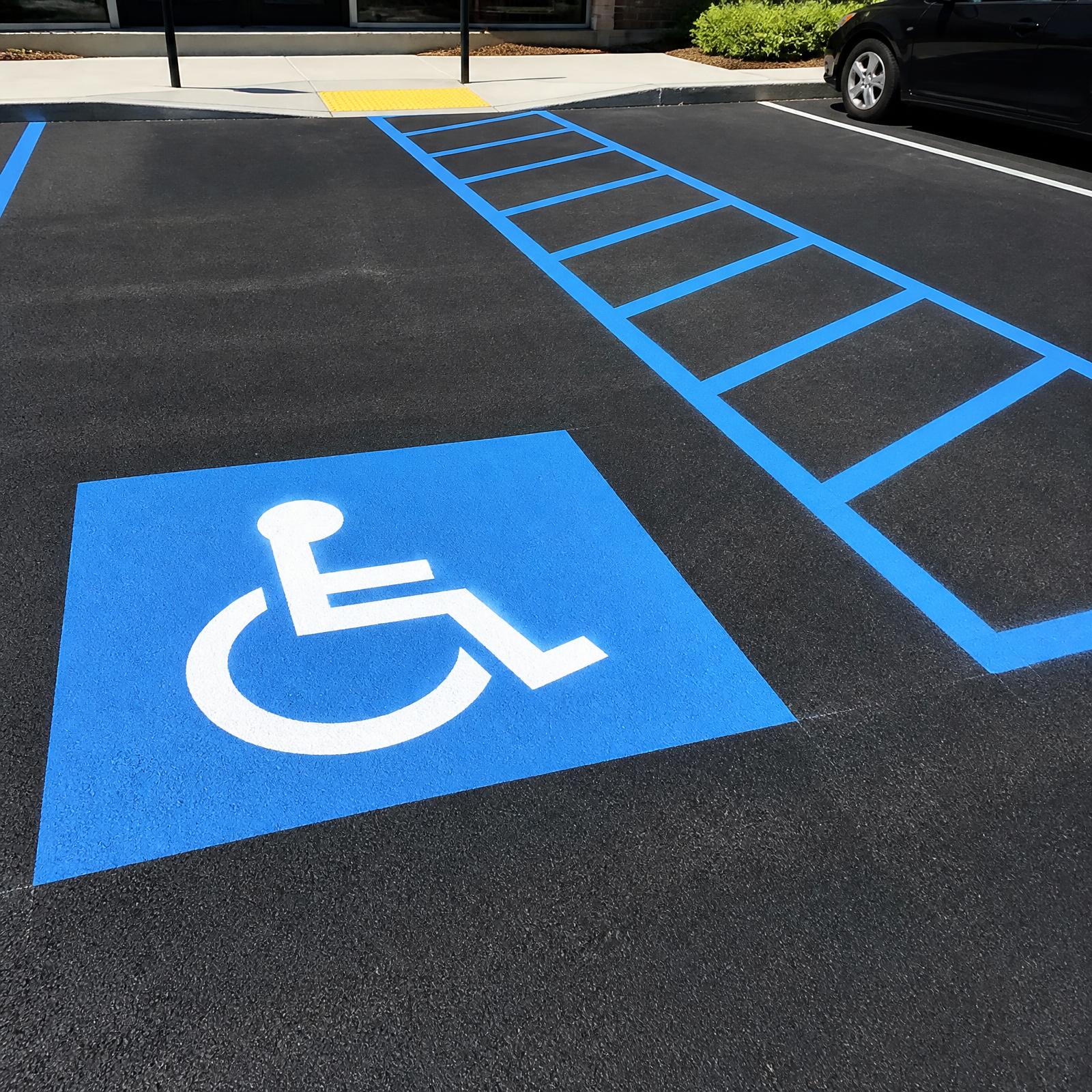 Freshly painted ADA accessible parking stall with blue wheelchair pictogram and van-accessible aisle hatching on new asphalt