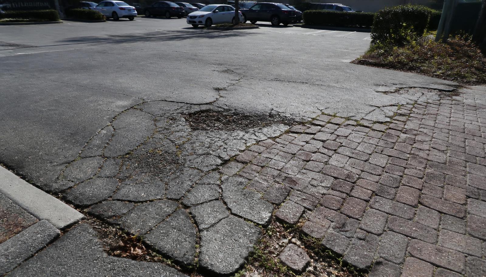 Damaged pavers needing parking lot asphalt repair in California